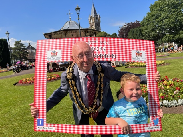Mayor in Victoria Gardens with head through a frame, with a child